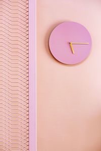 Low angle view of pink clock on wall
