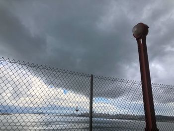 Low angle view of chainlink fence against sky