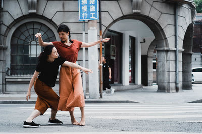 Full length of friends on street against buildings in city