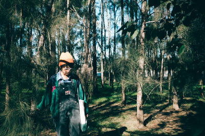 Young man standing amidst trees in forest