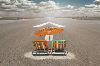 Digital composite image of deck chairs on sand and road with arrow symbol against sky