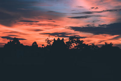 Silhouette trees against orange sky