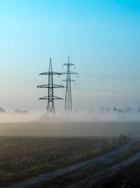 A foggy morning in an autumn field with a power line and a country road