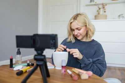 Portrait of young woman using mobile phone while sitting at home