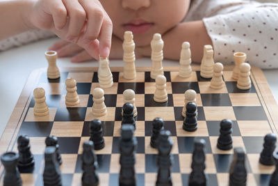 Midsection of girl playing chess at table