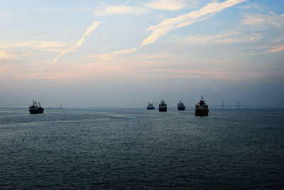 Boats at sea against sky during sunset