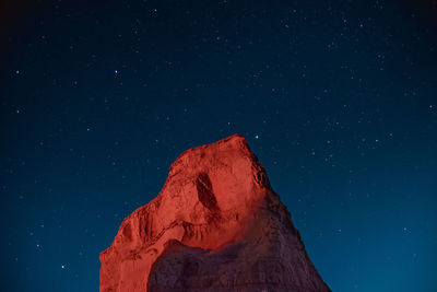 Low angle view of star field and a mountain against sky at night