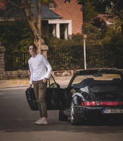 Portrait of young man standing by car