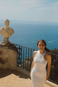 Portrait of young woman standing against sea