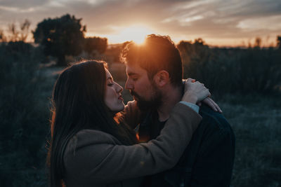 Couple kissing against sky during sunset