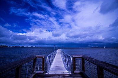 View of jetty leading to sea against cloudy sky