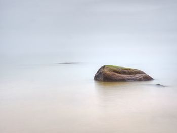 Rock in sea against sky