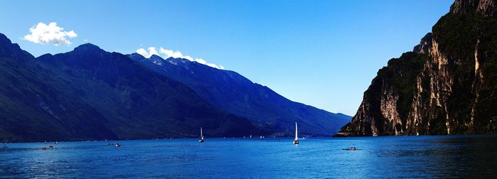 Scenic view of sea and mountains against blue sky