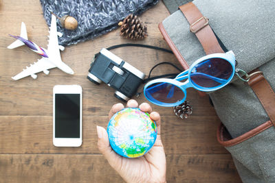 Cropped hand of man holding globe by personal accessories on table