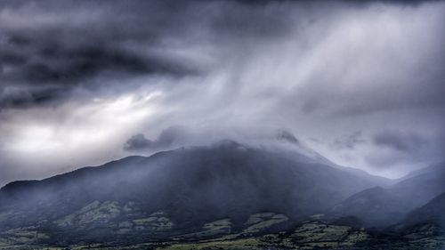 Scenic view of mountains against storm clouds