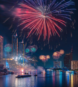 Low angle view of firework display over river at night