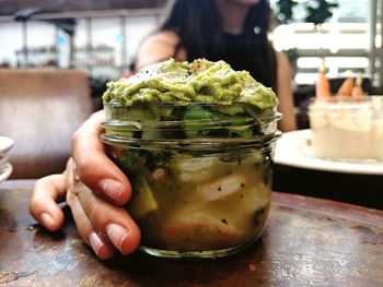 Close-up of hand holding guacamole in jar