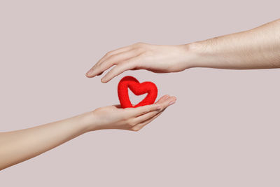 Cropped hand of woman holding red bell pepper against white background