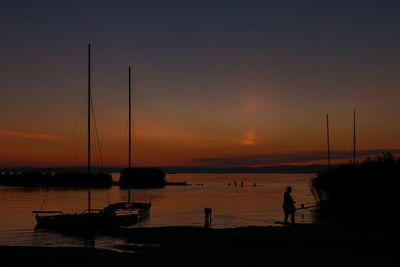 Silhouette sailboats moored on sea against sky during sunset