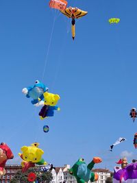 Low angle view of kites flying against blue sky