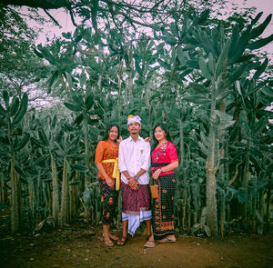 Full length portrait of friends wearing traditional clothing while standing on agricultural field