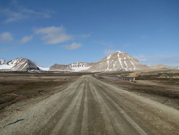 Road by mountain against sky