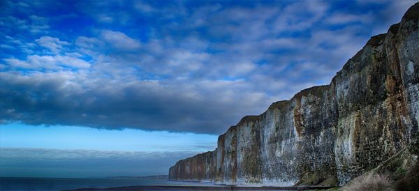 Low angle view of rock formation by sea against sky