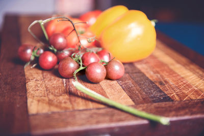 Close-up of cherry tomatoes by yellow bell peppers on table