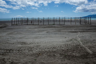 Wooden posts on beach against sky