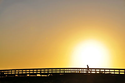 Silhouette bridge against sky during sunset