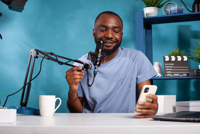 Smiling man blogging while using phone