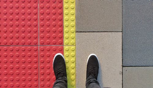 Low section of person standing on multi colored umbrella