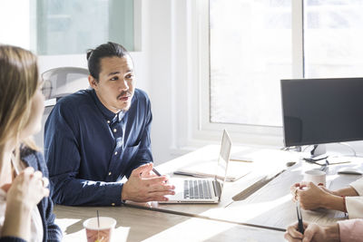 Colleagues discussing while sitting in board room