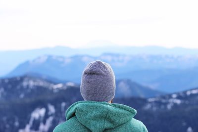 Rear view of man looking at mountains against clear sky