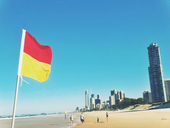 Red and yellow striped flag at beach against clear sky