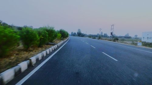 Road amidst trees against clear sky