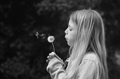 Side view of girl blowing dandelion