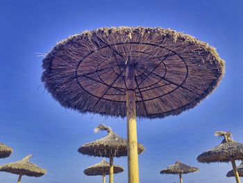 Low angle view of parasol against clear blue sky