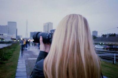 Rear view of woman photographing against cityscape