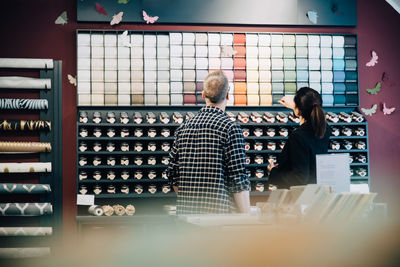 Rear view of salesman showing wallpaper to customer in store