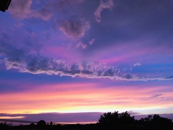 Silhouette trees against dramatic sky during sunset