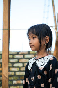 Smiling girl standing by stone wall