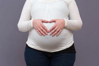 Midsection of woman touching face against gray background