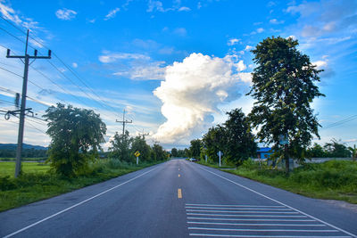 Empty road amidst trees against sky