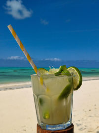 View of drink on glass at beach against sky