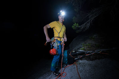 Man standing against illuminated wall at night