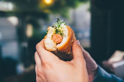 Cropped image of man eating hot dog