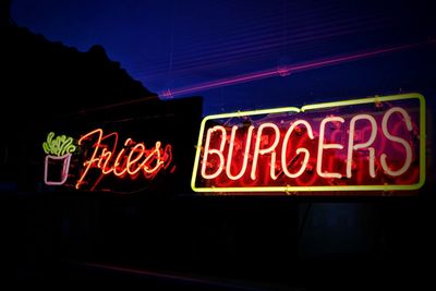 Illuminated neon text on window of cafe