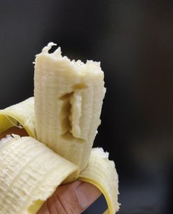 Close-up of hand holding ice cream cone against black background