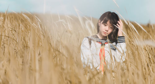 Young woman standing on field against sky